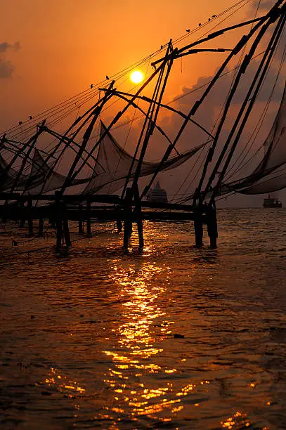 Sunset over Chinese Fishing nets and boat in Cochin (Kochi), Kerala, India.