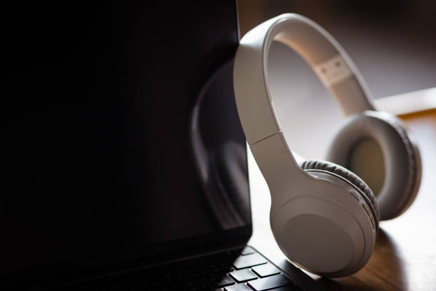 istock White headphones and laptop computer on wooden background 1494521340