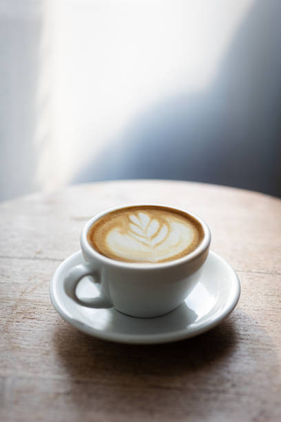istock Cup of hot latte on table by white curtain window in morning 1494521518
