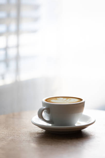 istock Cup of hot latte on table by white curtain window in morning 1494521521