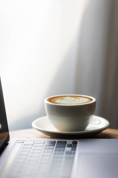 istock Start your working day with hot latte coffee cup background, laptop and mobile phone at work. 1494521543