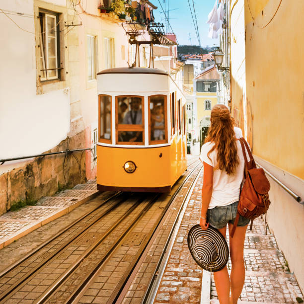 Mujer viajera esperando tranvía tradicional amarillo en una calle de Lisboa- Portugal - foto de stock