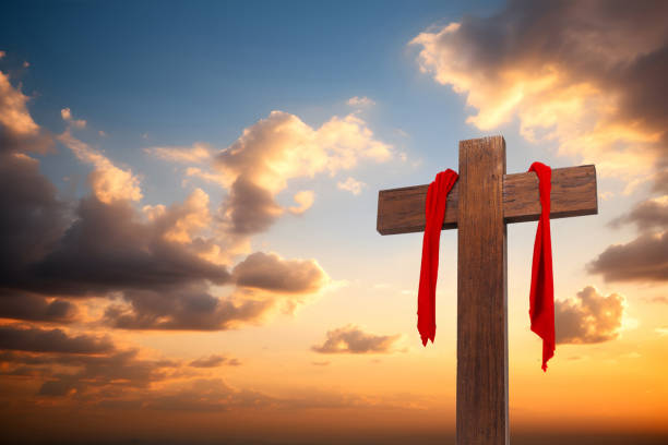 istock Wooden cross with red cloth wrapped around on sunset sky background 1494526527