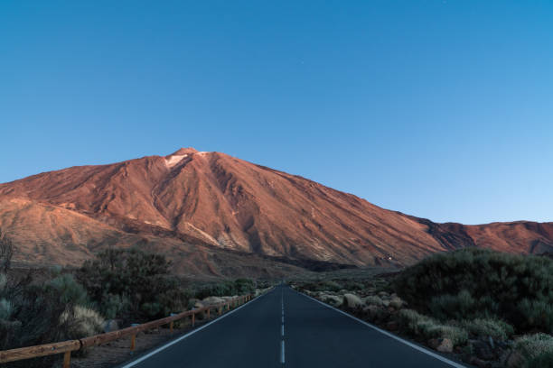 istock Straight street leading to huge Teide Vulcano with blue sky 1494526593