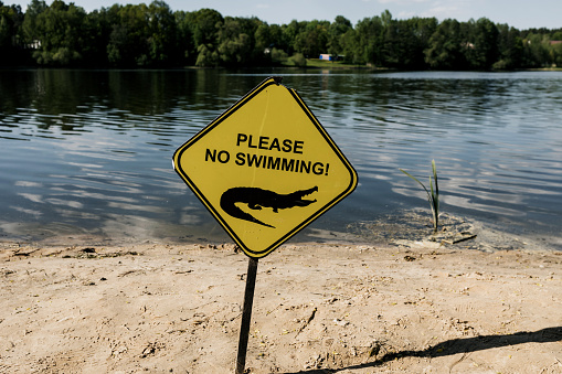 No swimming sign against the waves of lake. careful crocodiles