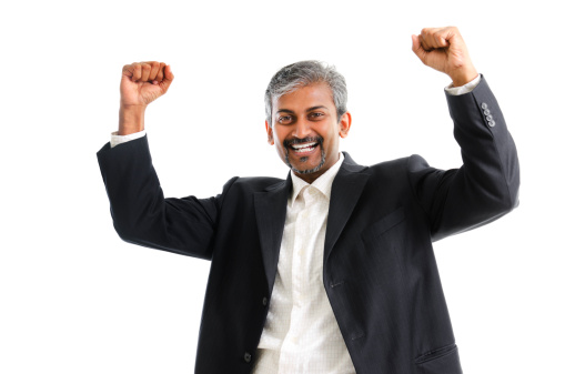 Portrait of excited Asian Indian businessman celebrating success over white background