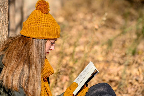 istock Girl sitting among some autumn trees, reading a book. 1494533638