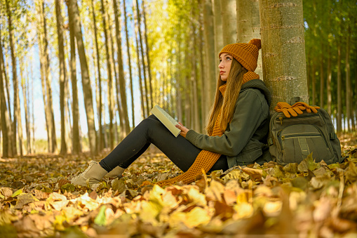 Girl sitting in a mall in autumn, reading a book