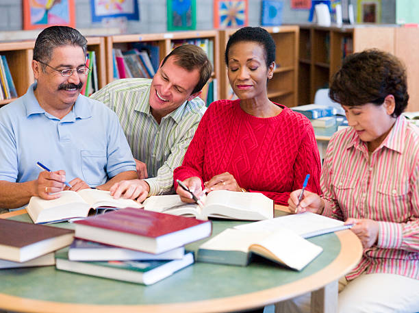 lehrer helfen ältere schüler in der bibliothek - adult student women mature adult library stock-fotos und bilder