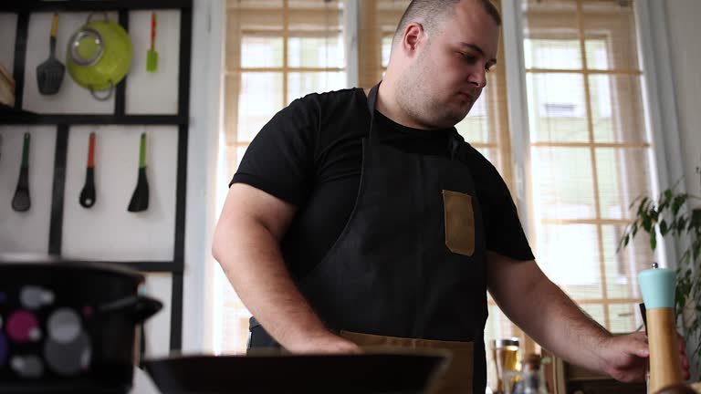 large build man adding spices on burgers