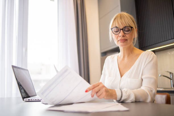 istock Mature woman using calculator while going through bills and home finances 1494534628