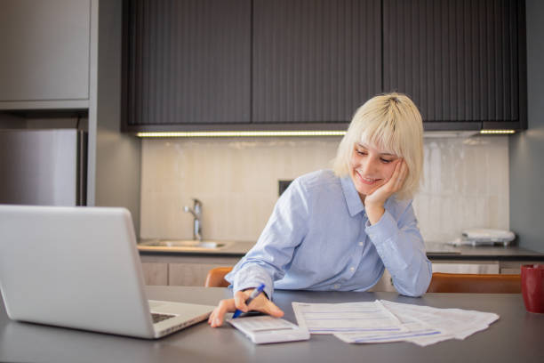 istock Young woman using calculator while going through bills and home finances 1494534660