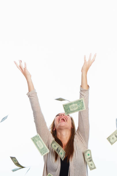 istock Dollars rain down on an ecstatic lucky woman with her arms raised 1494537088