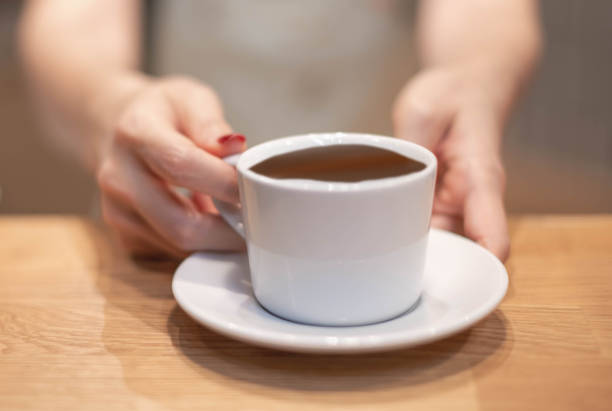 Female hand serve a cup of coffee to customer at the coffee shop. stock photo