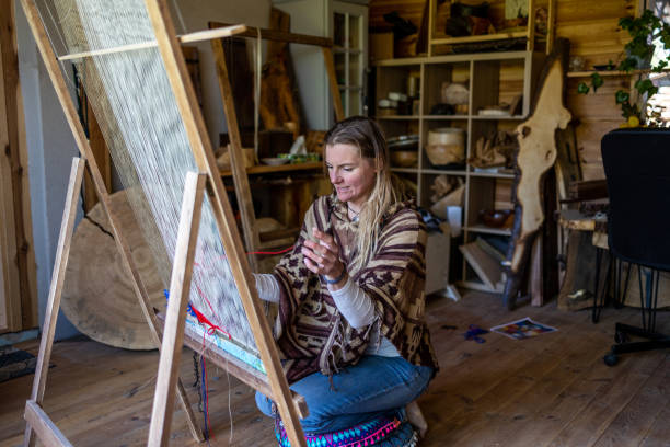istock Crafty woman weaving at a loom at her workshop 1494542375