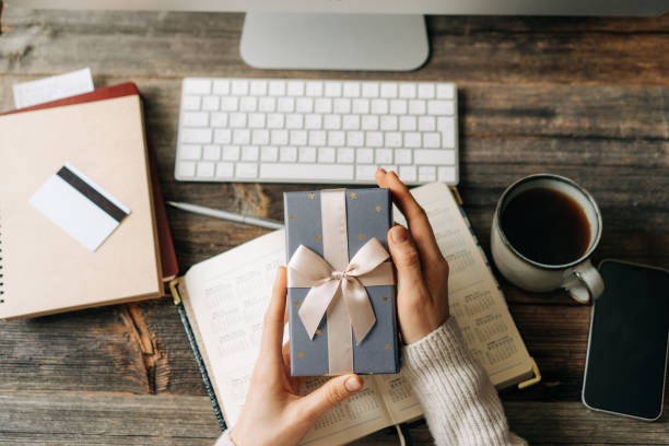 istock Top view of a gift box in female hands over a working office table. 1494543184
