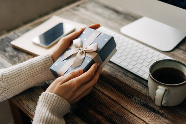istock Festive gift wrapping in female hands over a working office table. 1494543188