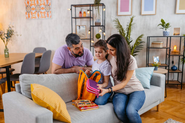 istock Daughter Packing Her Backpack For School With The Help Of Her Parents 1494544096