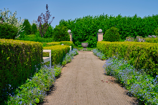 Tranquil green meadow with curved footpath with peacefully floating white clouds in the public park on Cape Cod in the summer.