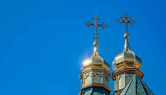 Two domes of church are covered with gold tin against a blue sky