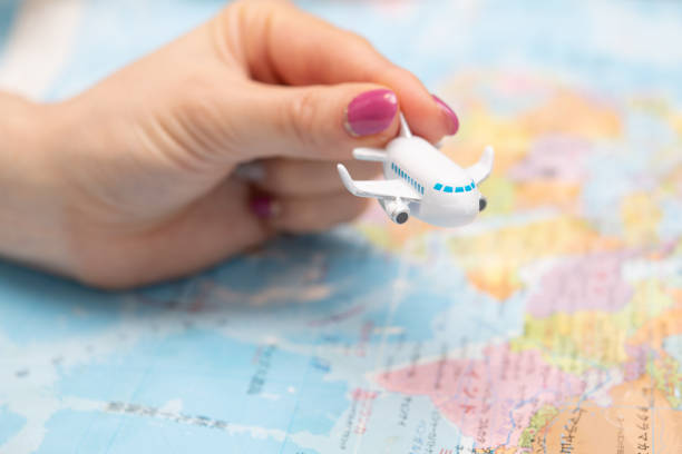istock Woman's hand holding toy airplane and world map 1494552602