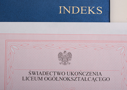 Polish high school graduation certificate without the red stripe and student record book, on the table closeup