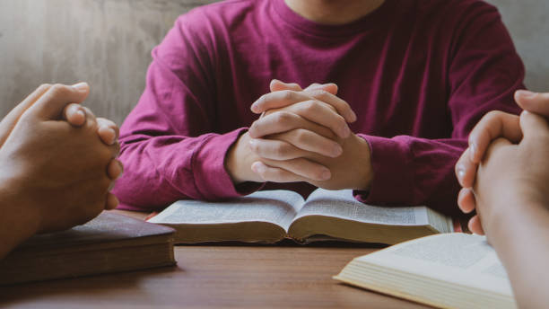 prayer meeting concept.colleagues shaking hands reading scriptures and praying to god at work place.prayer, trust, hope, gratitude concept - jesus christ human hand god consoling imagens e fotografias de stock