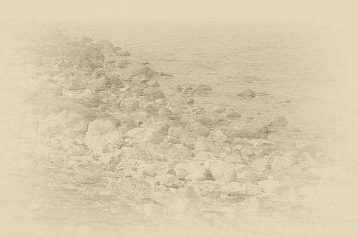 Dreamlike image of rocks by the sea in sepia