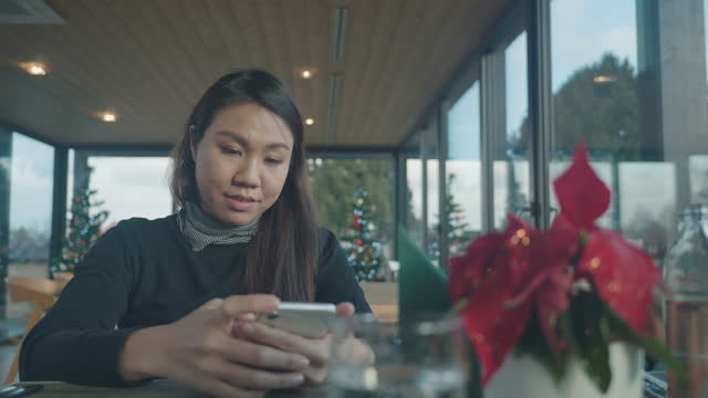 Woman playing mobile on Table set for Christmas