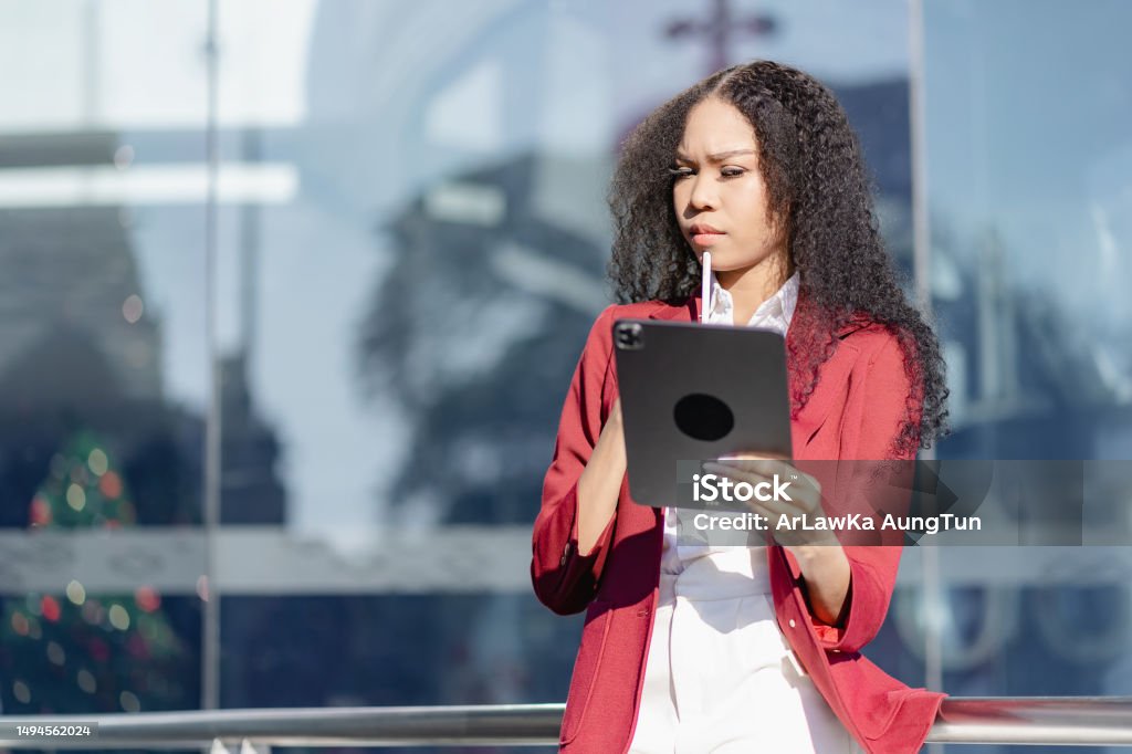 Glad kvinne som holder nettbrettet utendørs Afroamerikansk kvinne ved hjelp av digital enhet ser på kameraet smilende og jobber utendørs Adult Stock Photo