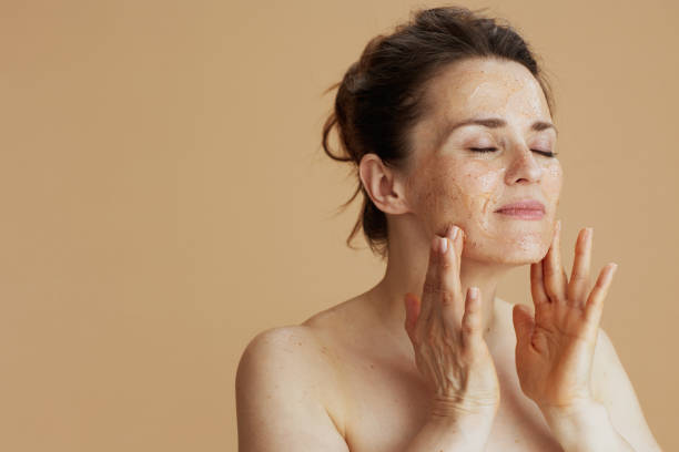 modern woman with face scrub against beige background stock photo