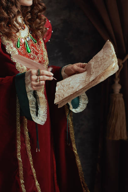 istock Closeup on medieval queen in red dress with parchment 1494564886