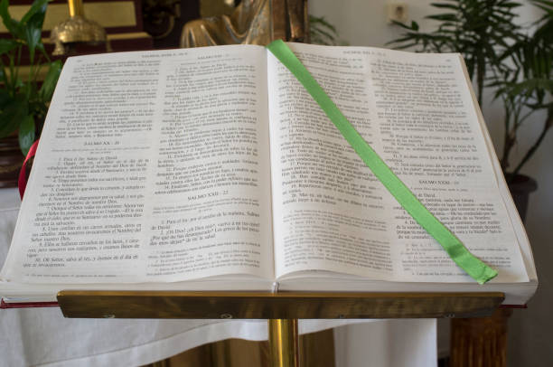 A candlestick, flower-filled vase, a cross and an open bible with marker ribbon displayed on the altar in the church of St Mary in Dallinghoo, Suffolk, Eastern England.