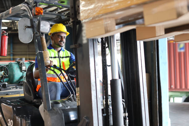 istock Warehouse workers or forklift driver man with hardhats and reflective jackets in vehicle using walkie talkie radio controlling stock and inventory in retail warehouse logistics, distribution center 1494568875