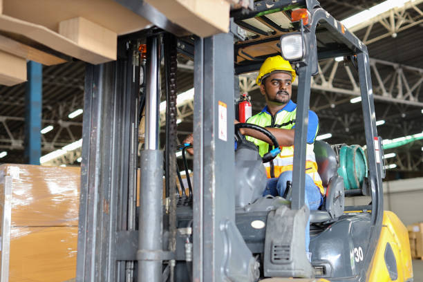 istock Warehouse workers or forklift driver man with hardhats and reflective jackets in vehicle using walkie talkie radio controlling stock and inventory in retail warehouse logistics, distribution center 1494568893