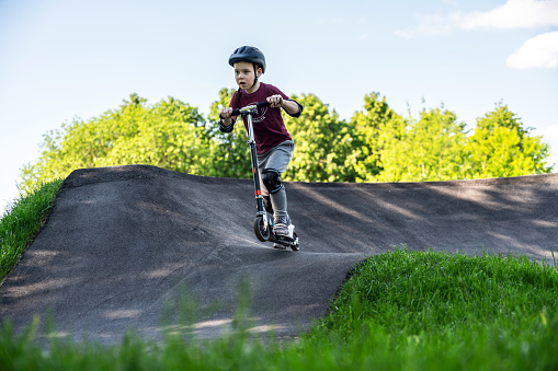 Boy riding push scooter at the outdoors pumptrack