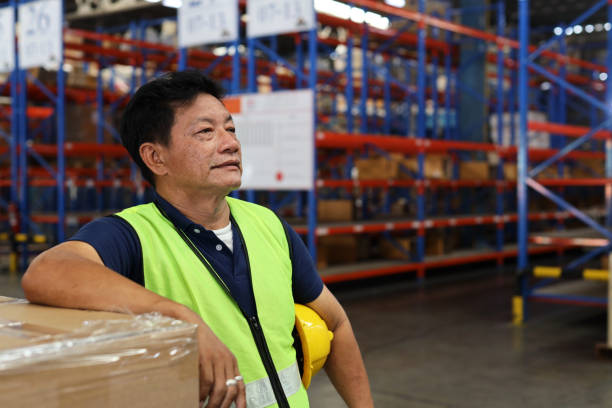 istock Asian warehouse workers man with hardhats and reflective jackets 
standing while looking away after controlling stock and inventory in retail warehouse logistics, distribution center 1494568899