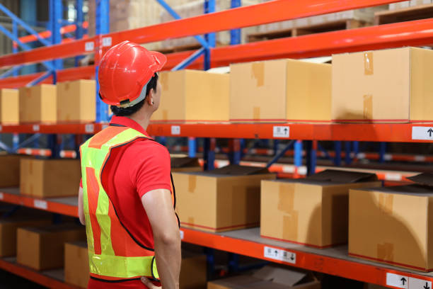 istock Warehouse workers man with hardhats and reflective jackets checking or controlling large box package for delivery to production stock and inventory in retail warehouse logistics, distribution center 1494569382