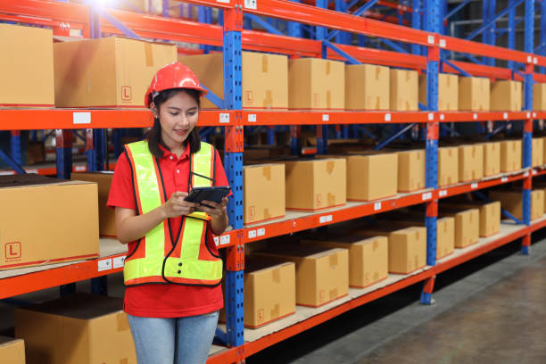 istock Warehouse workers woman in reflective jacket with tablet and checking or controlling large box package for delivery to production stock and inventory in retail warehouse logistics, distribution center 1494570604