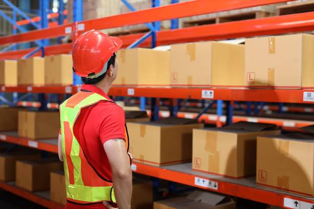 istock Warehouse workers man with hardhats and reflective jackets checking or controlling large box package for delivery to production stock and inventory in retail warehouse logistics, distribution center 1494570915