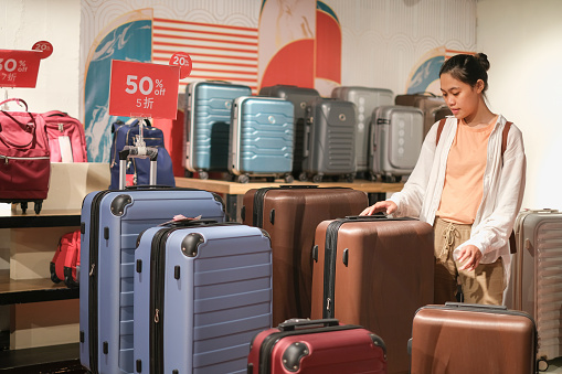 Young female traveler walking with a yellow suitcase at the modern Airport Terminal, Back view of woman on her way to flight boarding gate, Ready for travel or vacation journey