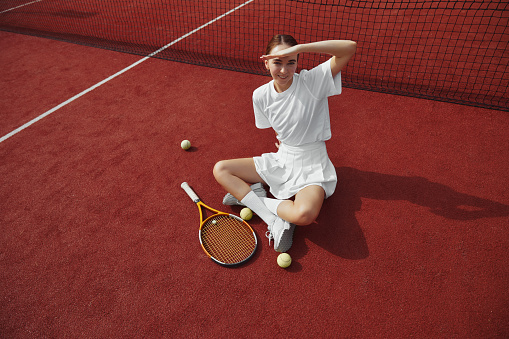 Young fit woman in a tennis skirt getting ready to serve. Waist down, holding a tennis racket.