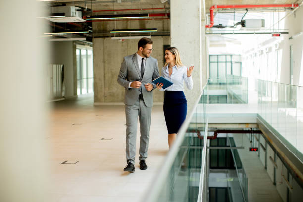 istock Young coworkers walking and talking along corridor in modern office 1494574933