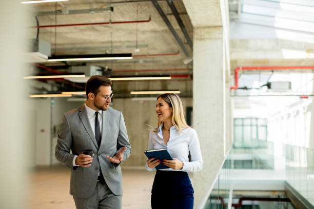 istock Young coworkers walking and talking along corridor in modern office 1494574967