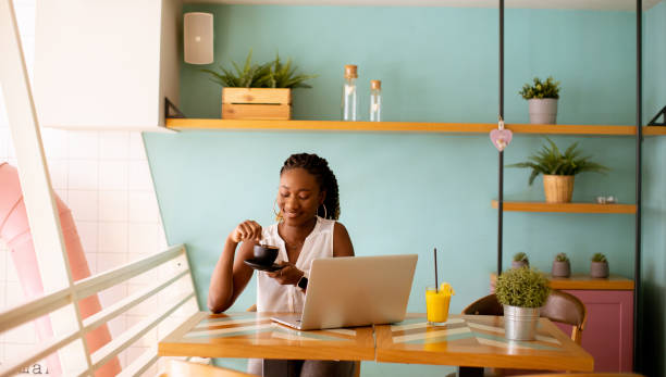 istock Young black woman drinking coffee  while working on laptop in the cafe 1494575056