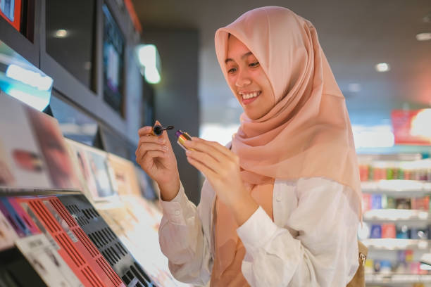 rossetto di shopping della donna indonesiana musulmana al negozio di make up - department store beautician cosmetics women foto e immagini stock
