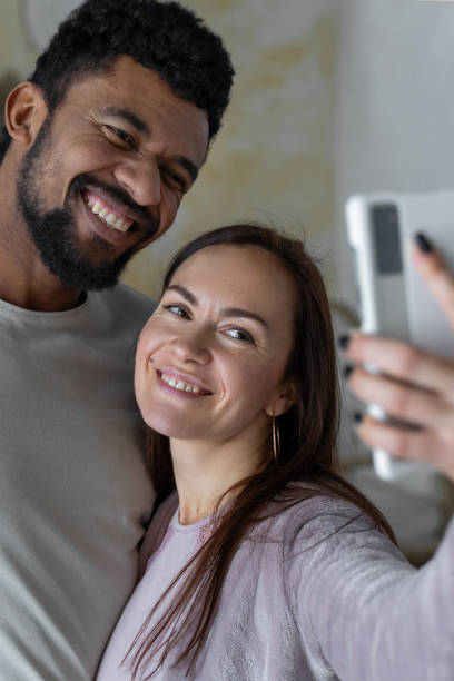 istock Multiethnic American couple using smartphone make selfie smiling at home 1494578137