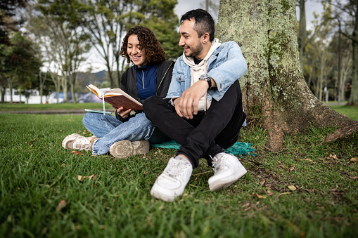 Young couple reading a book in the public park