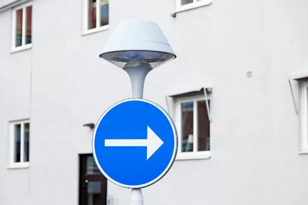 a lamppost with a round traffic sign with blue background and white arrow