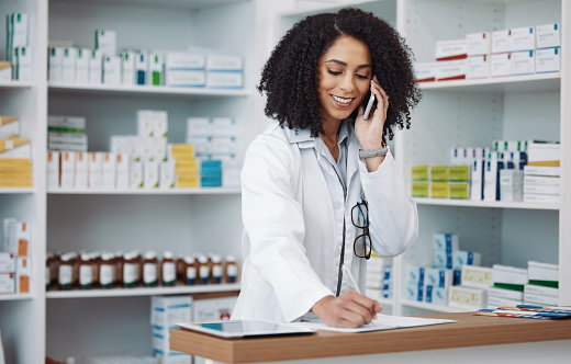 Phone call, counter and pharmacist woman for medicine note, customer service or virtual healthcare support. Happy, friendly doctor, medical retail person in pharmacy talking on cellphone at help desk